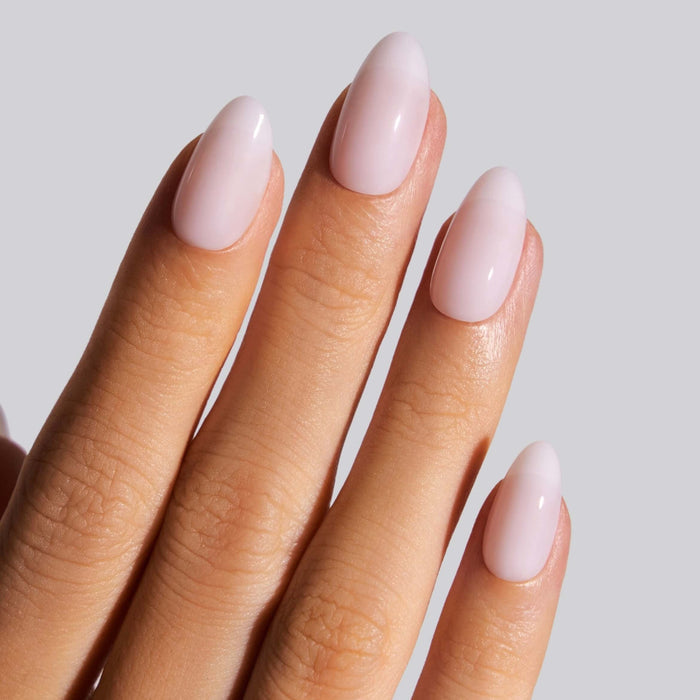 Ballerina short almond press-on nails in pale pink worn on model's hand against neutral background