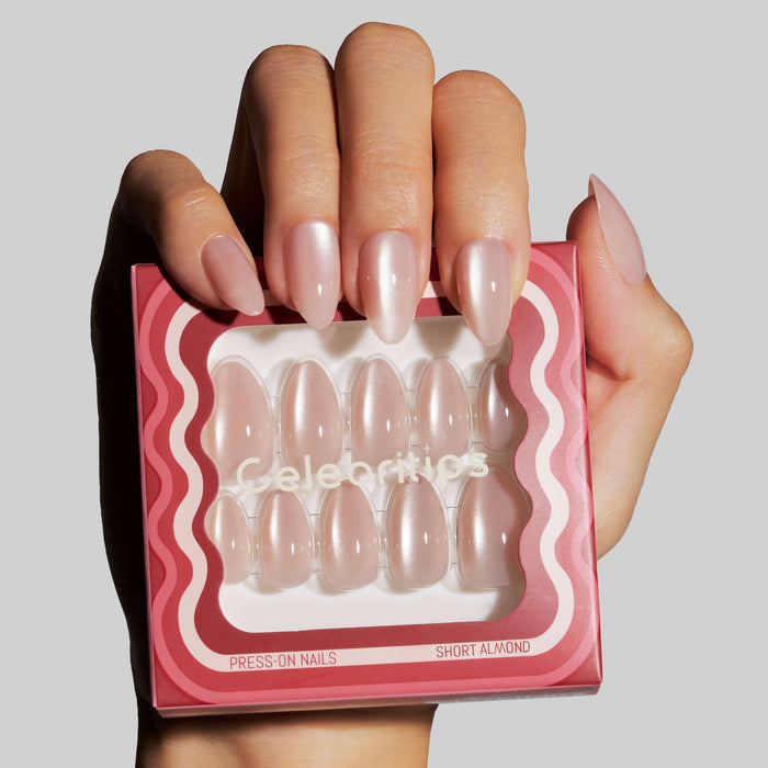Model holding Celebritips press-on nails in short almond shape with pink pearl finish in packaging
