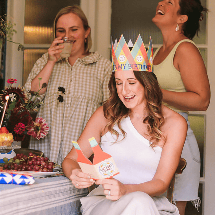 Person wearing birthday party hat with text "it's my birthday" at a celebration