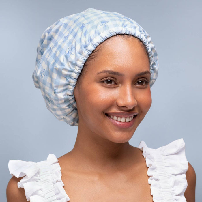 Woman wearing blue gingham satin-lined shower cap with ruffled white sleeves