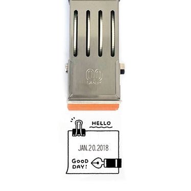 An imprint from a rotary stamp that shows the date, surrounded by a border decorated with a hand drawn binder clip and fountain pen, as well as the words Hello and Good Day!