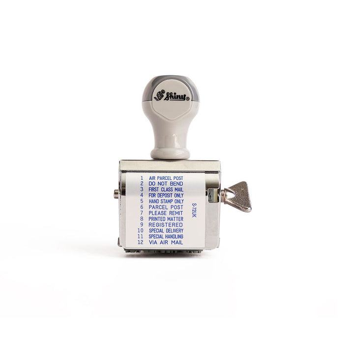 A rotating handheld stamp showing the following phrases: 
1.	AIR PARCEL POST
2.	DO NOT BEND
3.	FIRST CLASS MAIL
4.	FOR DEPOSIT ONLY
5.	HAND STAMP ONLY
6.	PARCEL POST
7.	PLEASE REMIT
8.	PRINTED MATTER
9.	REGISTERED
10.	SPECIAL DELIVERY
11.	SPECIAL HANDLING
12.	VIA AIR MAIL