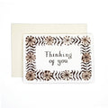 Greeting card reading “Thinking of you” with a brown botanical border, shown with a cream envelope.