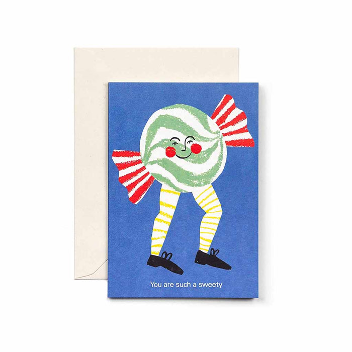 Greeting card with a smiling illustrated candy character on a blue background, reading “You are such a sweety,” shown with a cream envelope.